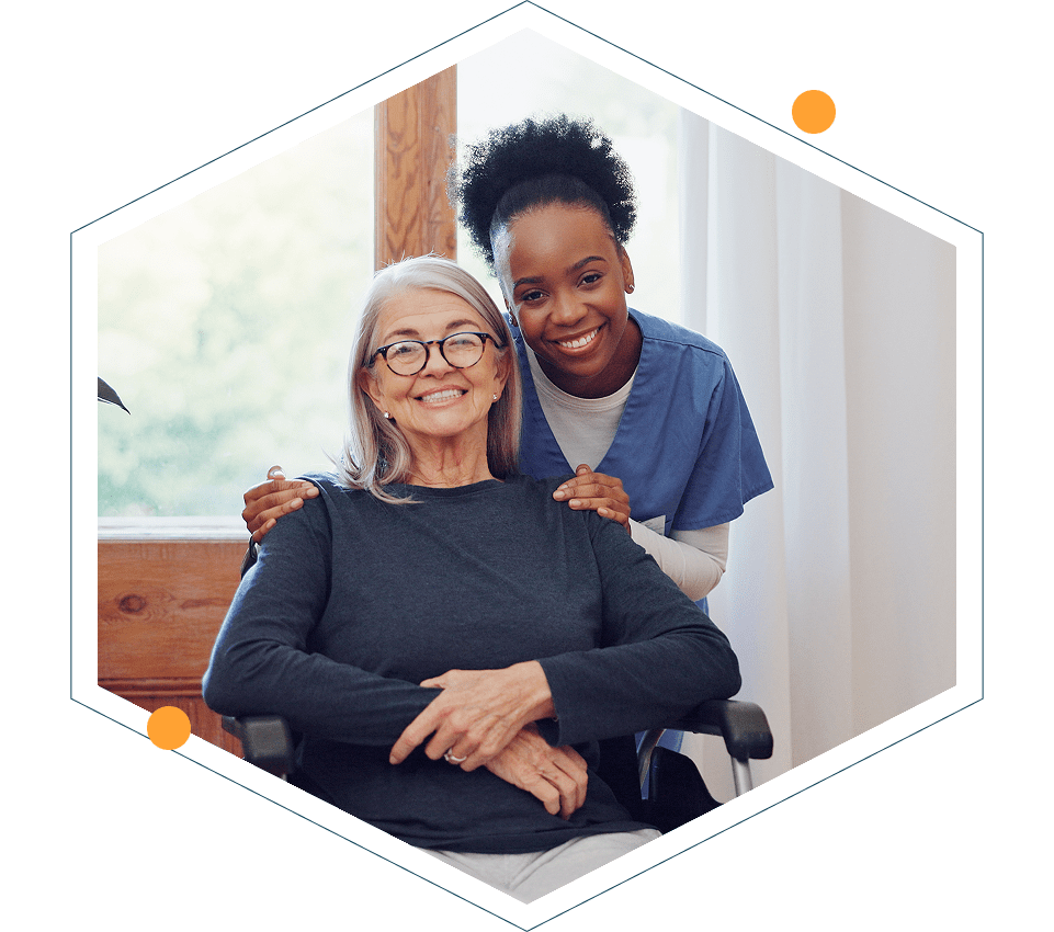 Caregiver with elderly woman, both smiling warmly.